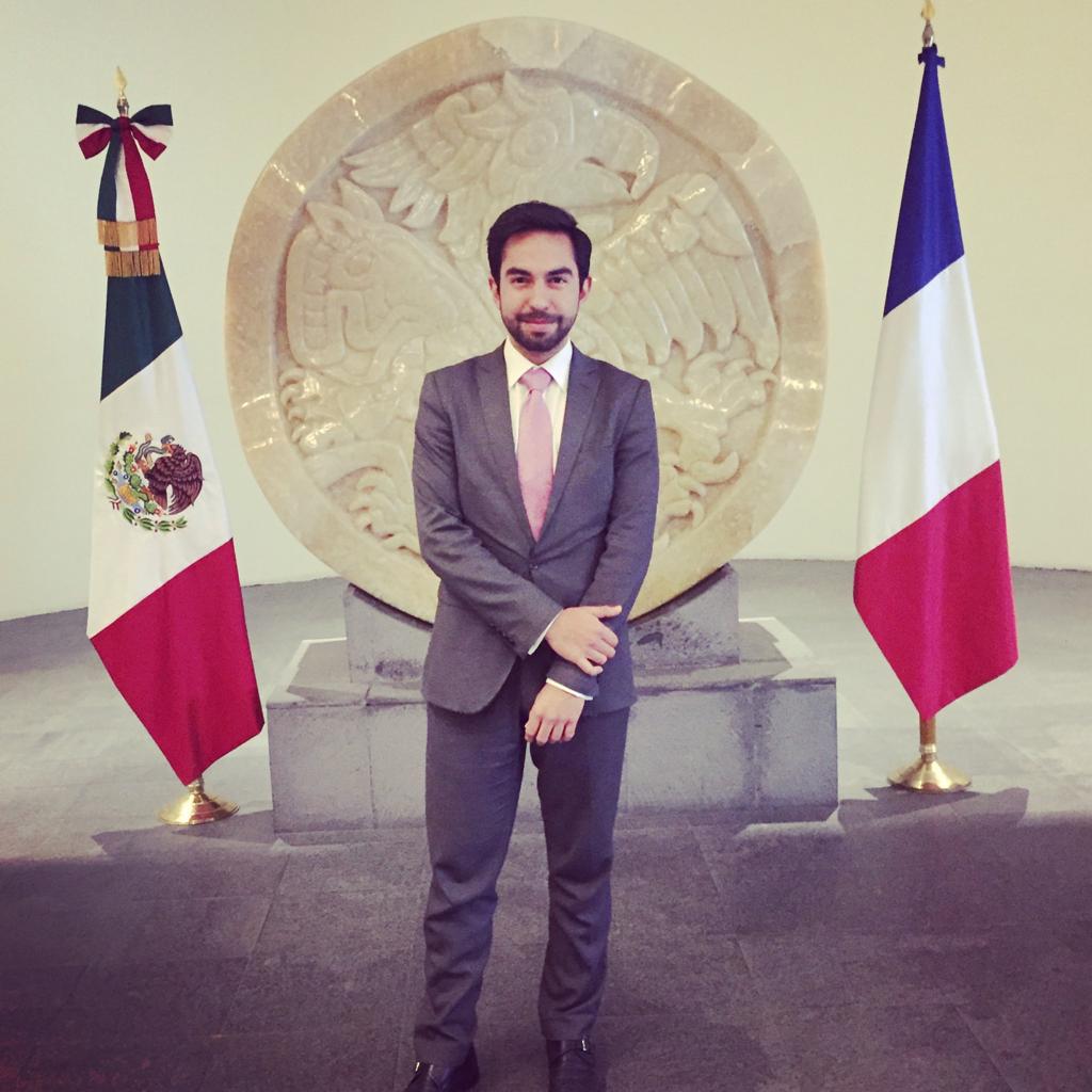 A man stands in front of two flags