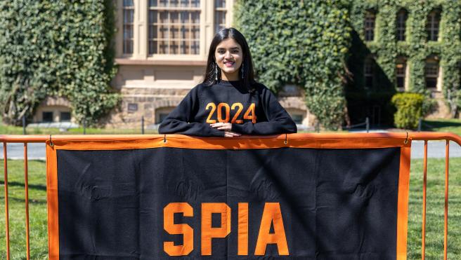 Uma Menon standing behind a SPIA banner.