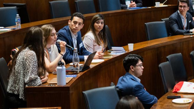 students sitting in auditorium watching student with mic