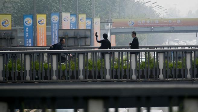 Three people on a bridge.