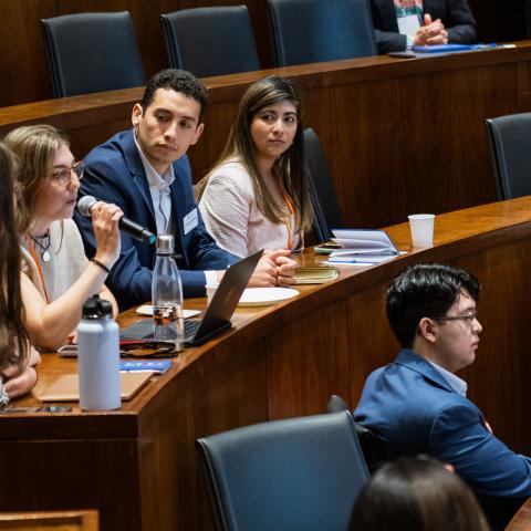 students sitting in auditorium watching student with mic