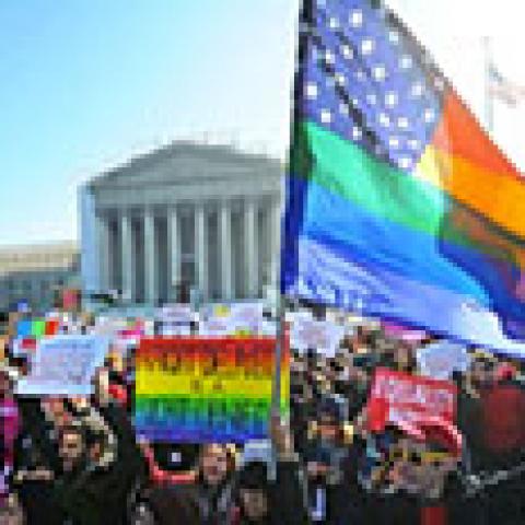 crowd in front of court house holding a rainbow American flag