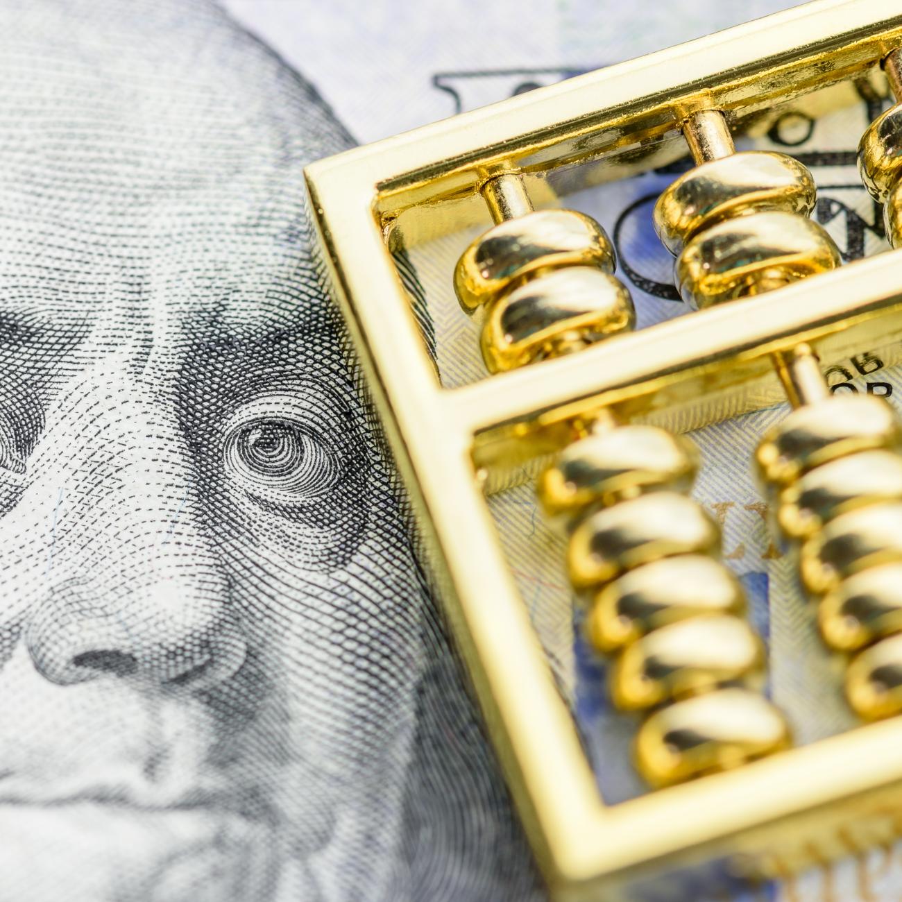 abacus in foreground with Benjamin Franklin in hundred dollar bill in background
