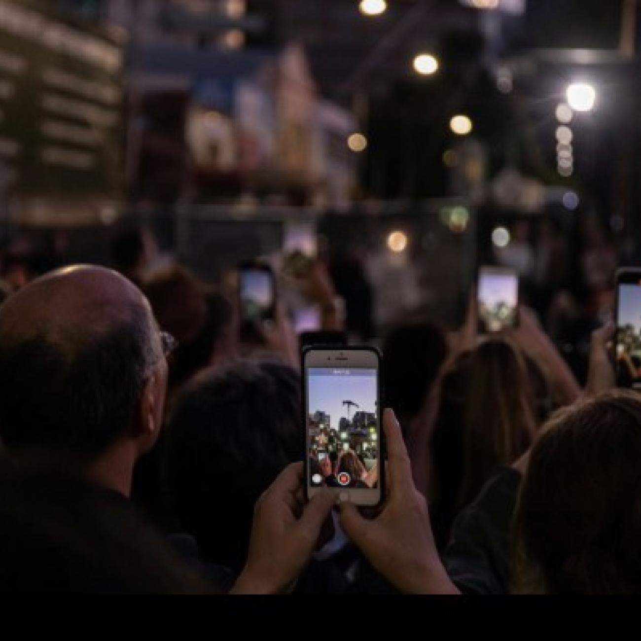 people holding mobile phones in a crowd
