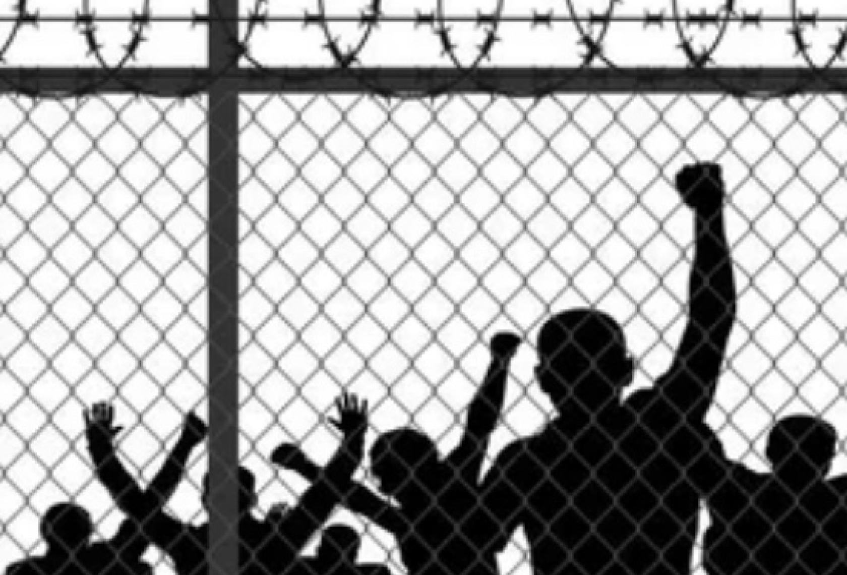 people with arms raised behind a wired fence in black and white