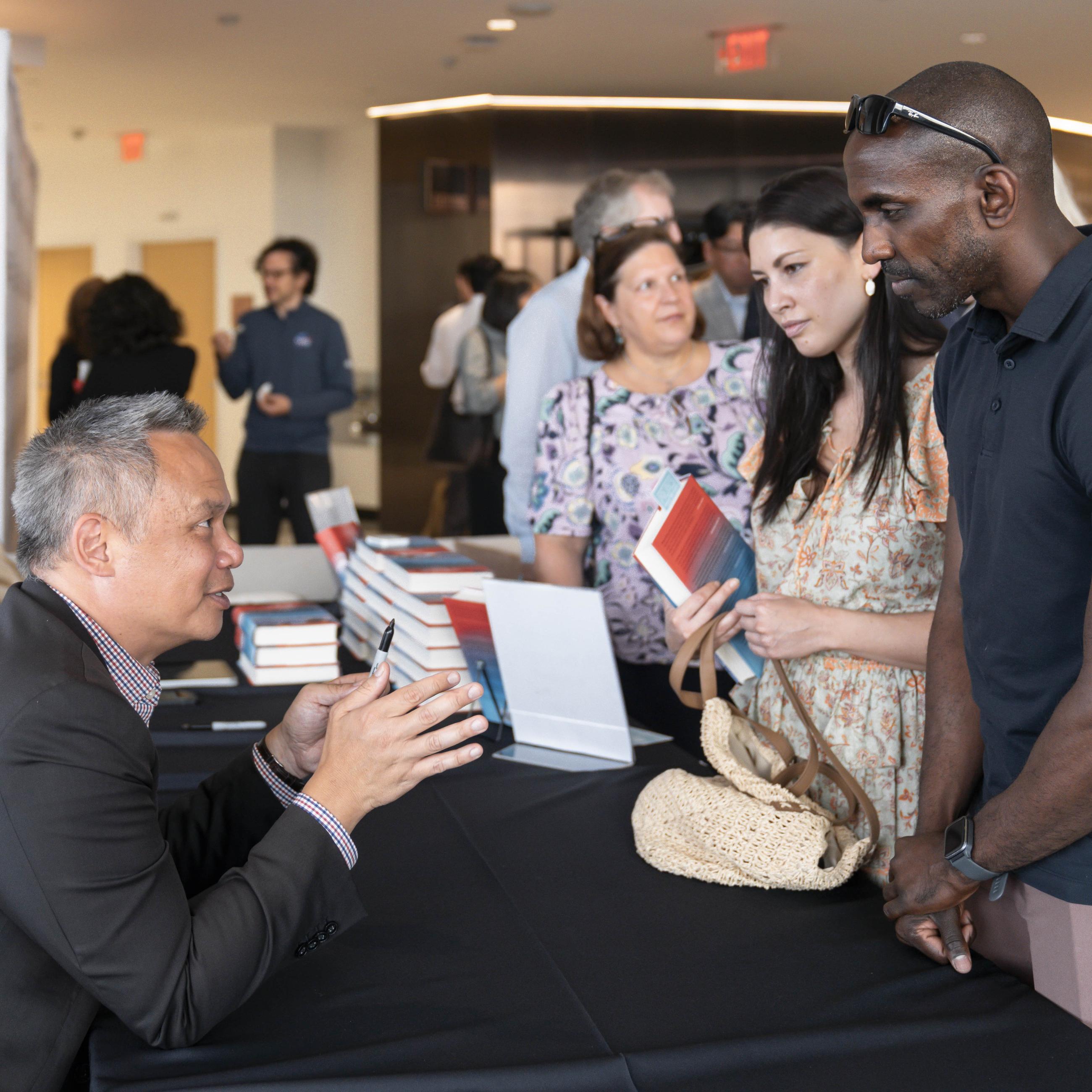 Edward Wong speaking with guests at book event