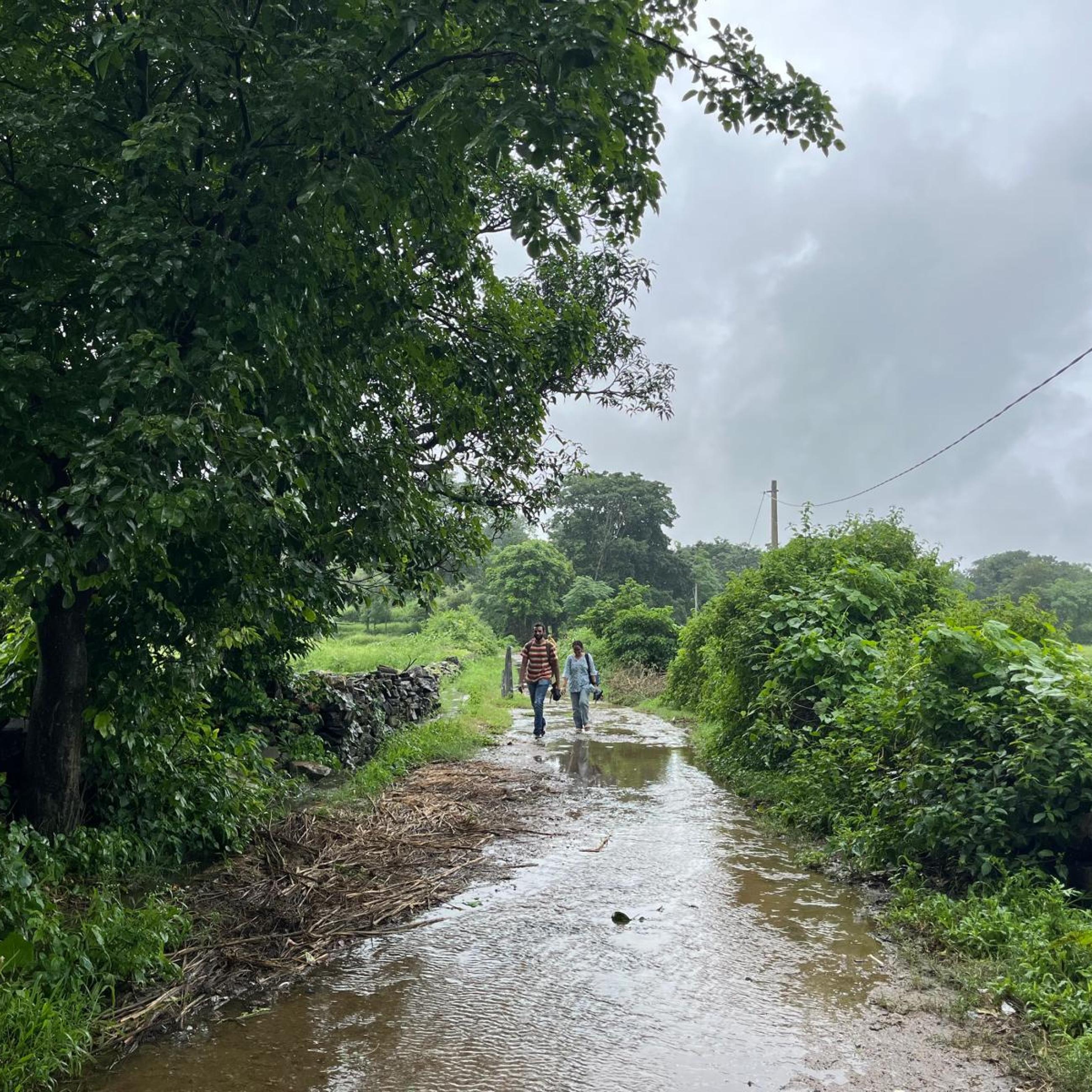 Two people walking on wet road in rural India